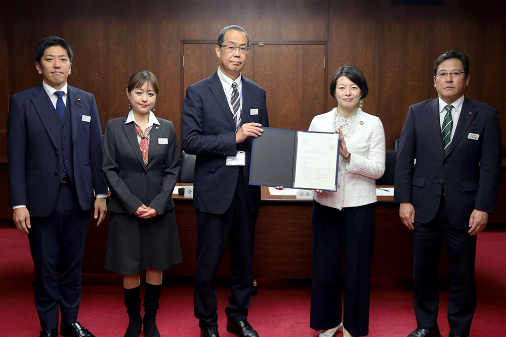 報告書を手に記念撮影している画像